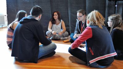 Jugendliche sitzen auf dem Boden im Kreis und tauschen sich aus, wie Jugendbeteiligung für ihren Stadtteil aussehen kann.