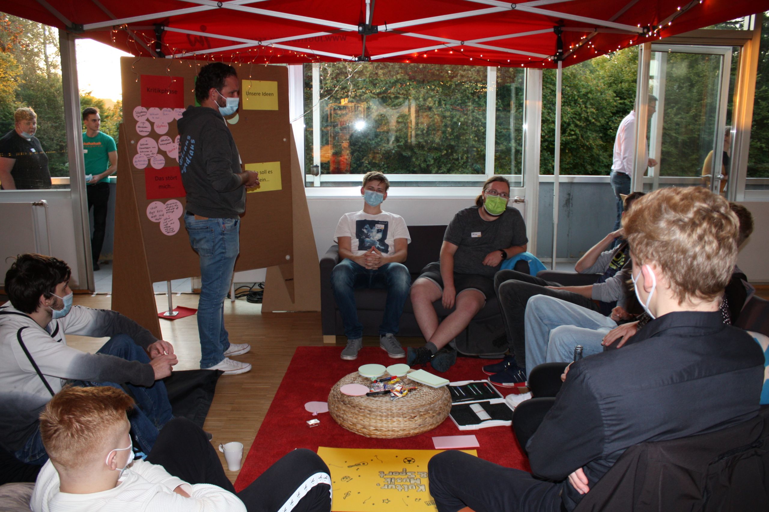 Jugendliche sitzen zusammen im Kreis bei einem Jugendforum. In der Mitte liegen Zettel mit Ideen für Jugendbeteiligung in ihrem Stadtteil.